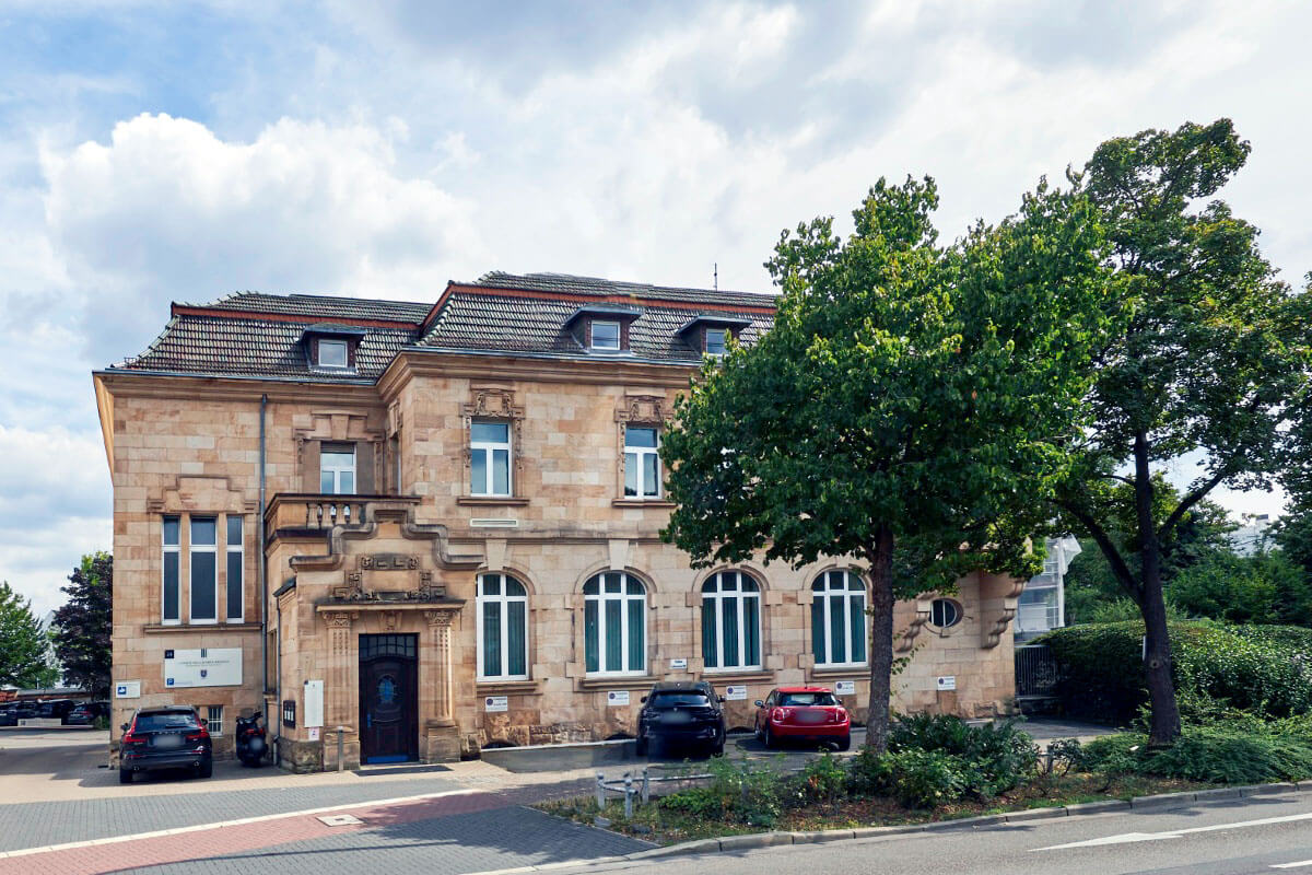 Blick von oben in ein modernes Treppenhaus mit mehreren Etagen und h&auml;ngenden Deckenleuchten.